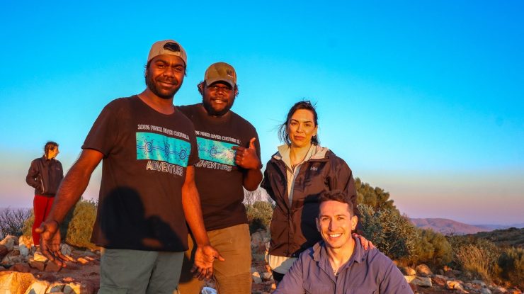 First Nations guides from 100% Finke River Culture & Adventure share a moment with travellers on the Larapinta Trail, surrounded by the stunning landscapes of Tjoritja (West MacDonnell Ranges). An authentic and enriching experience, connecting culture, community, and Country with Inspiration Outdoors.