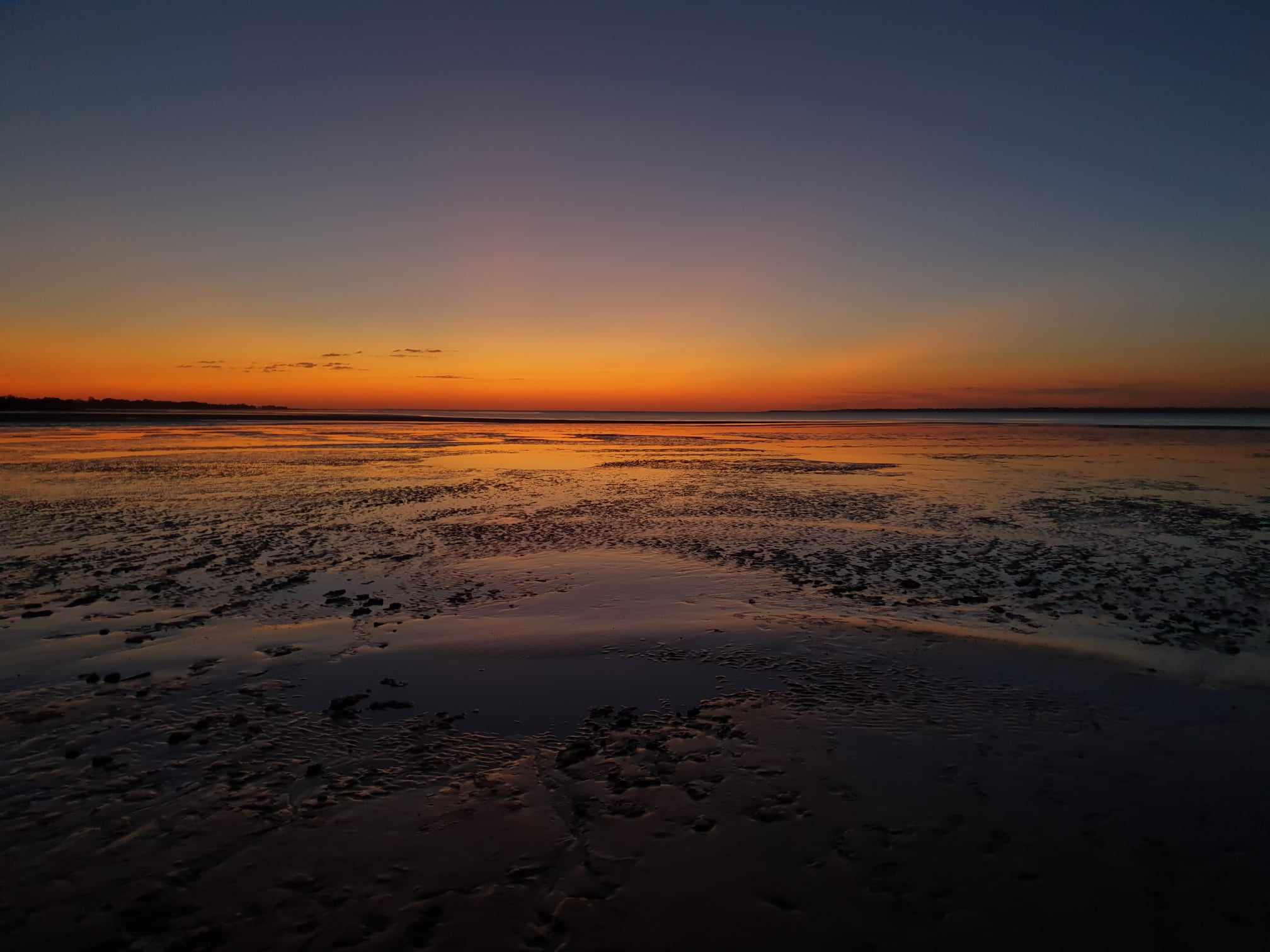 A breathtaking sunset over the tidal flats of Weipa, Cape York, Queensland, with golden hues reflecting off the water and mudflats, captured during an Inspiration Outdoors adventure.