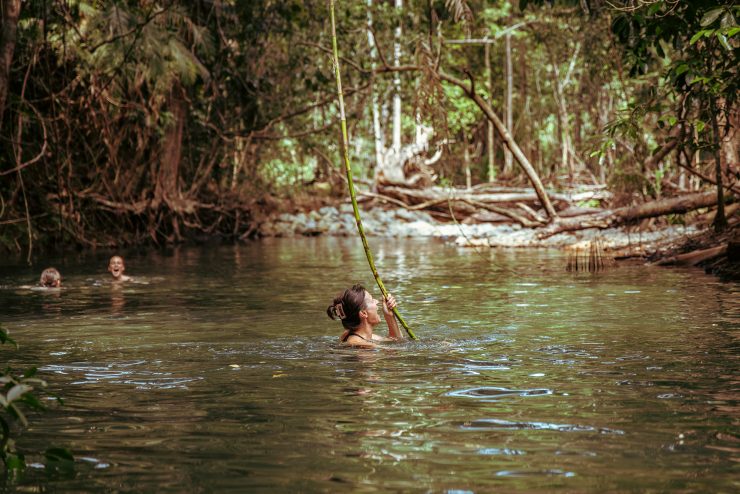 Travellers from Inspiration Outdoors enjoy a refreshing swim and laughter in a serene natural swimming hole surrounded by lush rainforest in Daintree National Park, Cape Tribulation.